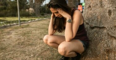 一個女生蹲在樹旁苦惱
