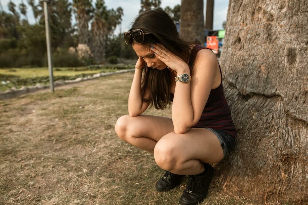 一個女生蹲在樹旁苦惱