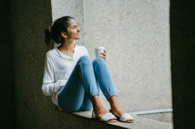 一個女生坐在窗邊喝咖啡