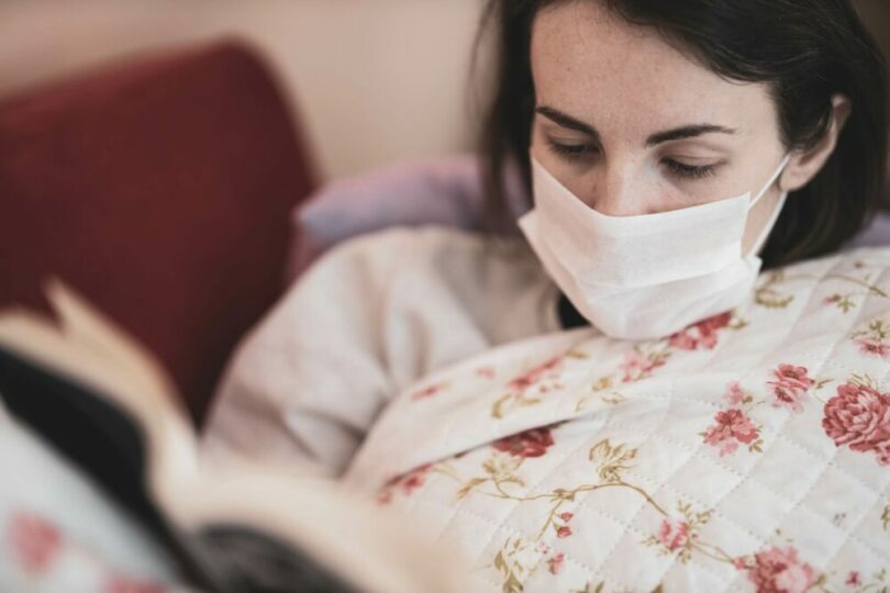 一個女生戴著口罩在看書