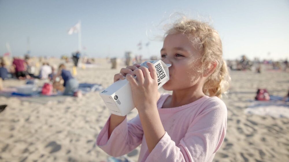 一個小女孩在沙灘上喝飲料
