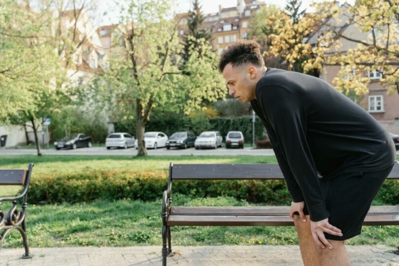一個男人在公園旁半蹲握住膝蓋