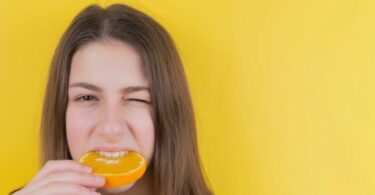 一個女生在咬一片橘子