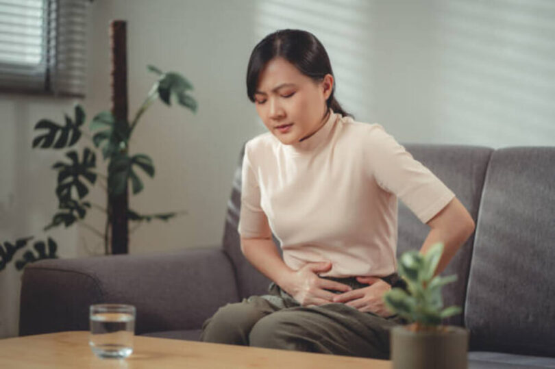 一位女士手摸著腸胃
